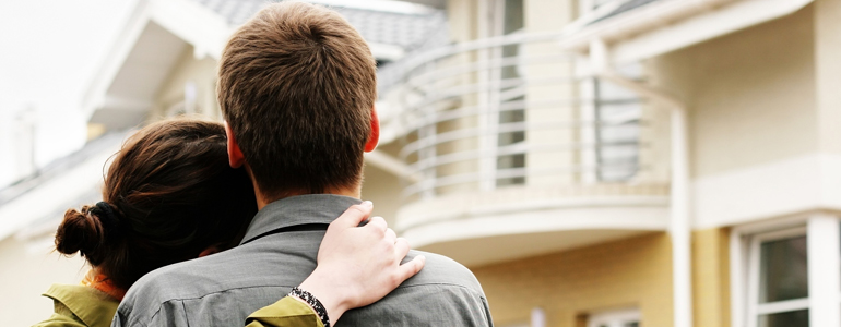 Couple hugging outside home 