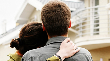 Couple hugging each other in front of home 